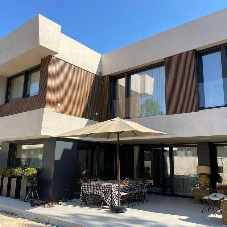 Mặt tiền villa phối các mảng tường sáng với phần hoàn thiện tông gỗ ở khối phía trên và khu hiên.