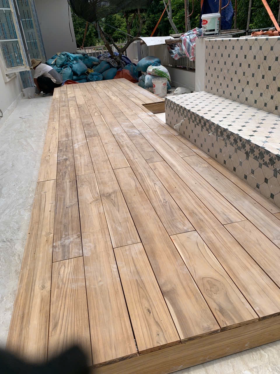 Toàn cảnh sàn Teak Lào chạy dọc hông villa, nối khu cửa nhà với khoảng vườn xanh cuối hiên.