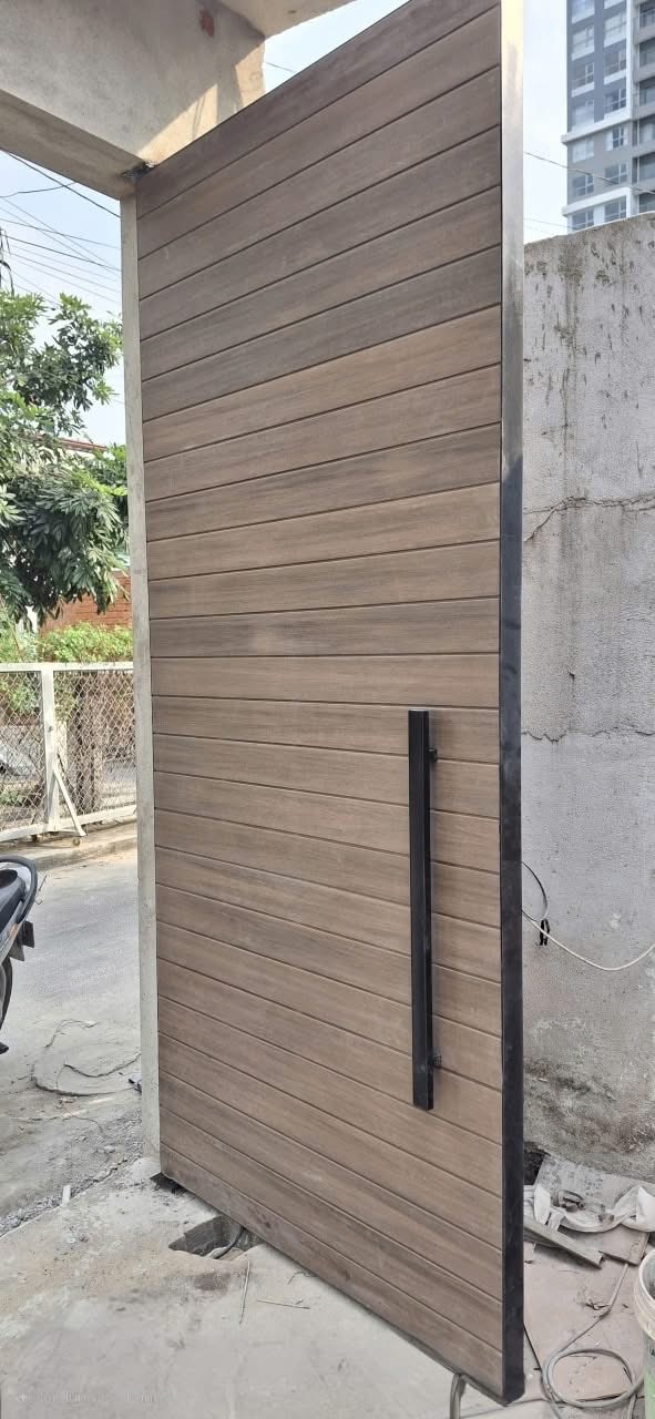Cánh cổng đơn tông gỗ với các thanh ngang và tay nắm dài màu tối.