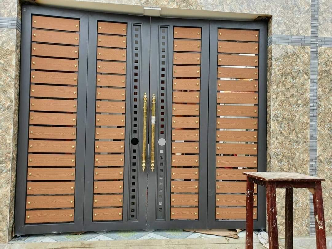 Bộ cổng nhiều cánh tại mặt tiền, phối các mảng nan tông gỗ với khung và trụ màu tối.