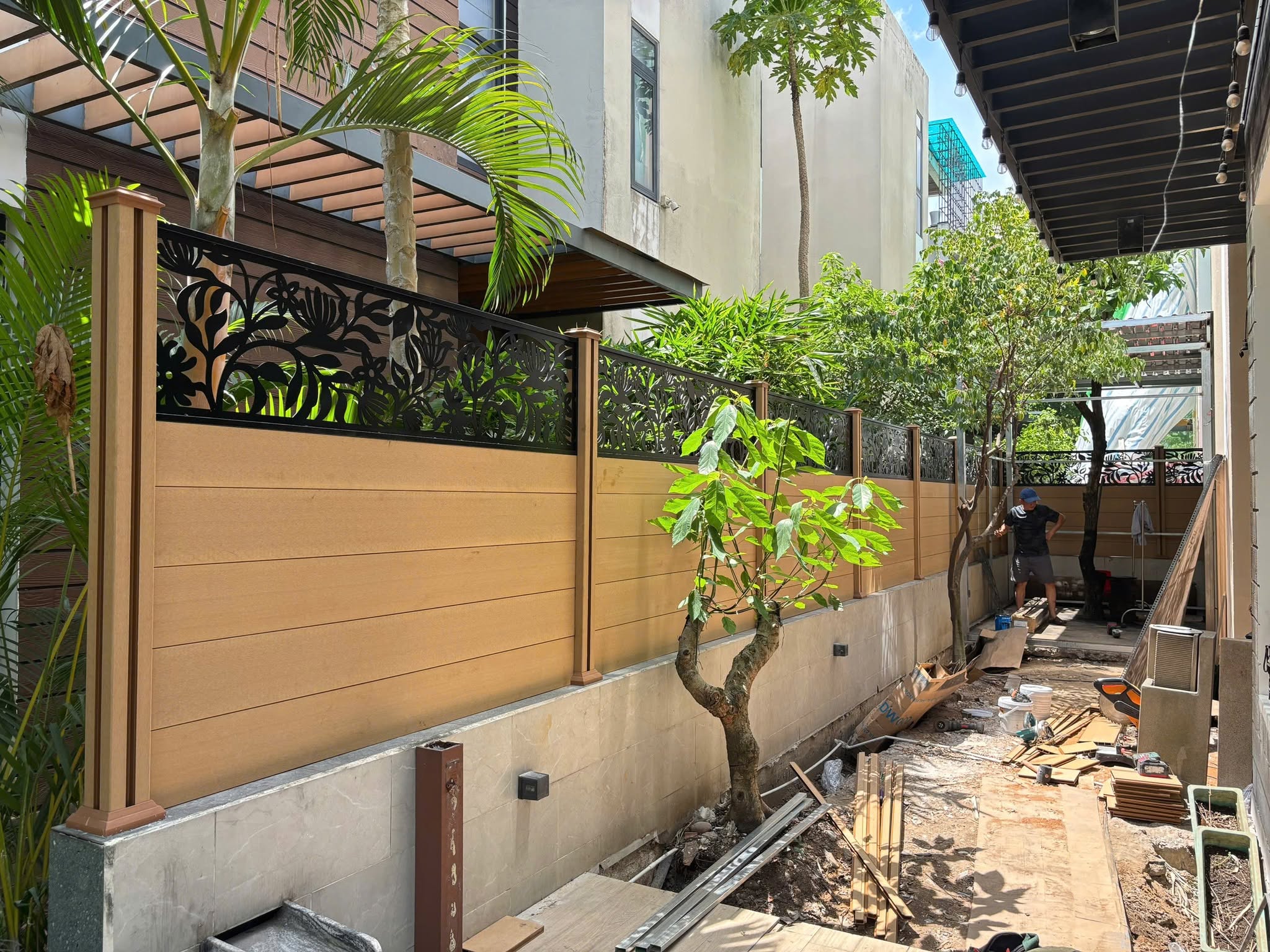 Công trình đang thi công hàng rào kết hợp mảng kín và ô hoa văn, với vật tư còn tập kết ở phần sân