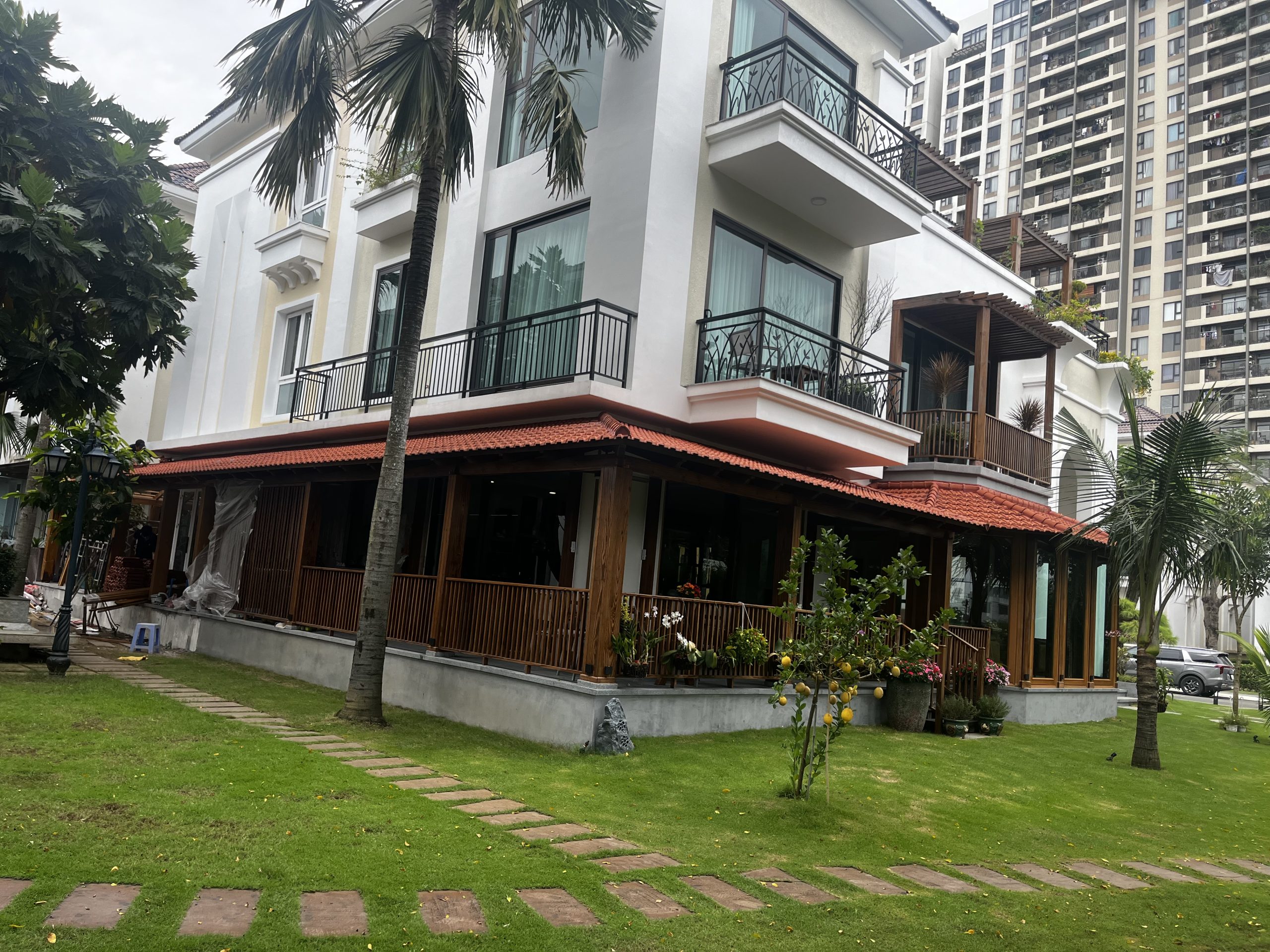 Toàn cảnh mái hiên gỗ bên ngôi nhà và sân cỏ